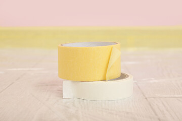 Rolls of masking tape on floor near masked baseboard, closeup