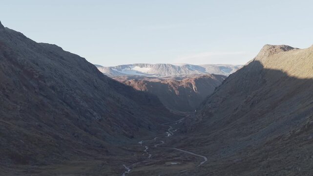 Lifting drone footage of valley an snow cowered mountains in Jotunheimen National Park, Norway