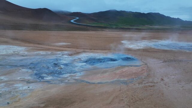 Aerial view of hverir geothermal area with boiling hot spring fields at dark cloudy day. Road in mountains in distance. Iceland, Europe.