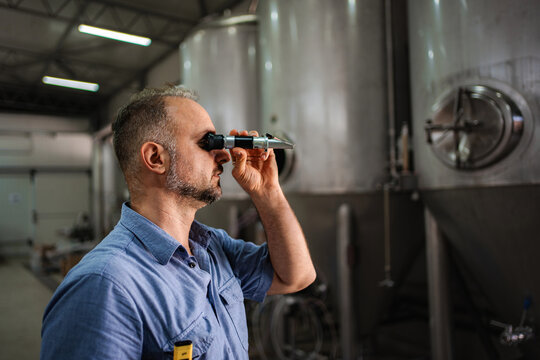 Man using refractometer checking beer quality at brewery