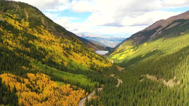 The Canadian Rockies stretch across the horizon as brilliant aspens fill the valley and peaks reflect in alpine lakes under crisp blue autumn light.
