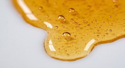 Viscous golden fluid with trapped air bubbles glistening atop a bright surface