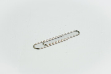 A single classic silver paper clip, isolated on a stark white background. A symbol of simplicity, organization, and a minimalist aesthetic.