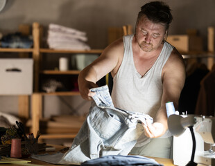 Middle-aged male dressmaker reviewing jeans to restore