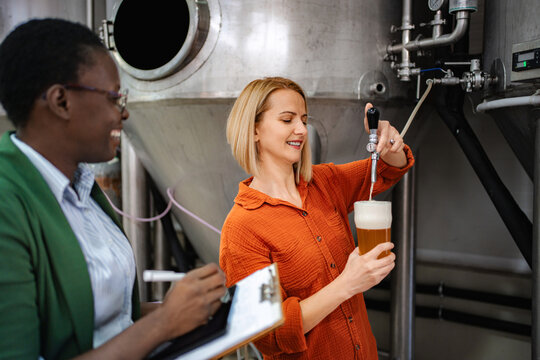 Women pouring beer during quality control inspection in brewery