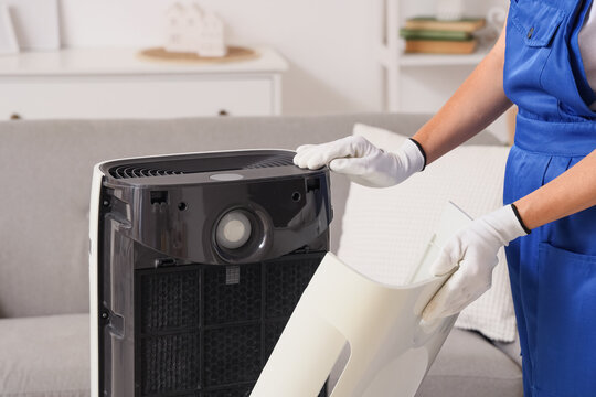 Female technician changing dirty air purifier filter at home