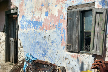 Close-up detail of weathered blue painted wall with wooden shutters and peeling paint texture
