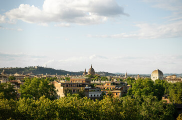 Fototapeta premium Panoramic cityscape view of Rome with historic architecture and green trees under blue sky