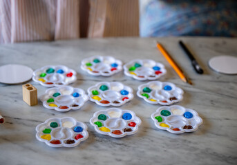 Colorful paint palettes with brushes and pencils on marble table ready for art activity