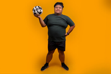 Full Length of Happy Overweight Man Holding Soccer Ball Isolated on Yellow Background
