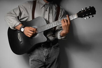 Obraz premium Young man playing acoustic guitar on grey background