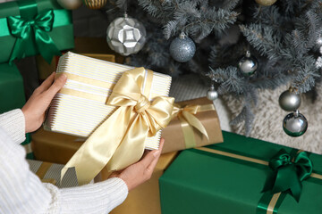 Female hands with presents under Christmas tree at home, closeup