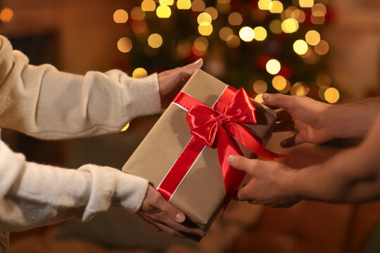 Hands of couple with beautiful gift box at home on Christmas eve, closeup