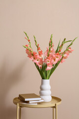 Books and vase with bouquet of beautiful gladiolus flowers on table in living room, closeup