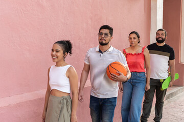 Group of friends walking and smiling with basketball and skateboard
