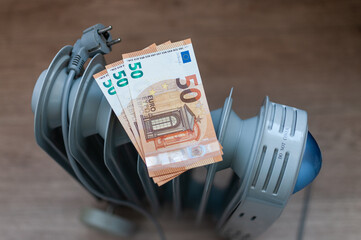 Euro banknotes lie on an electric radiator, symbolizing the high cost of electricity and heating. Rising energy prices. Concept of an energy crisis. Social problems. 