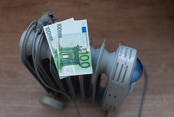 Euro banknotes lie on an electric radiator, symbolizing the high cost of electricity and heating. Rising energy prices. Concept of an energy crisis. Social problems. 