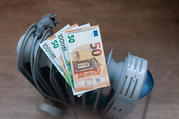Euro banknotes lie on an electric radiator, symbolizing the high cost of electricity and heating. Rising energy prices. Concept of an energy crisis. Social problems. 