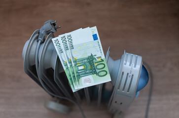 Euro banknotes lie on an electric radiator, symbolizing the high cost of electricity and heating. Rising energy prices. Concept of an energy crisis. Social problems. 
