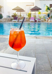 Aperol Spritz cocktail glass by swimming pool