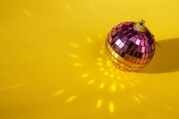 Shiny Colorful Disco Ball with Reflected Light on Yellow Background. Party Decorations for Christmas
