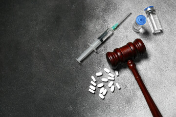 Judge gavel with pills, ampules and syringe on grunge grey background. Concept of health care reform