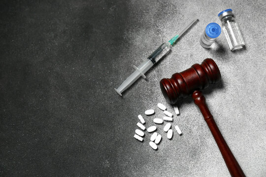 Judge gavel with pills, ampules and syringe on grunge grey background. Concept of health care reform - Powered by Adobe