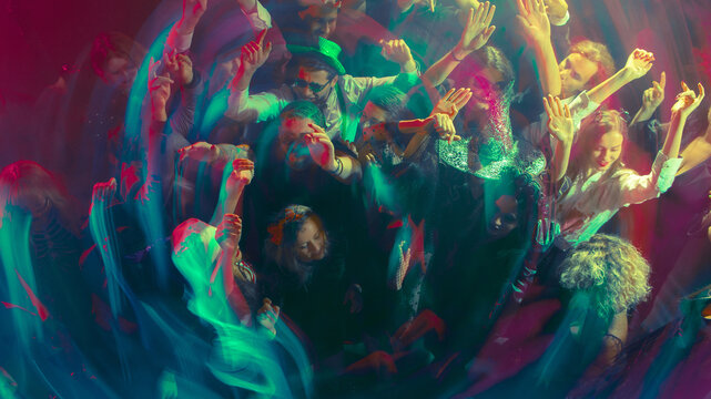 People dancing in neon lights with vibrant motion blur energy. Concept of nightlife, Halloween fashion, and freedom for lifestyle, entertainment, and event branding visuals.