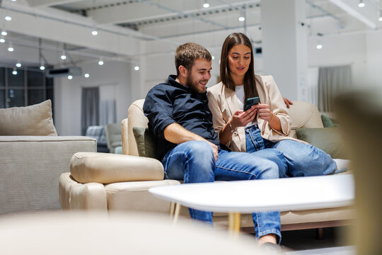 Young couple shopping online for furniture on smartphone