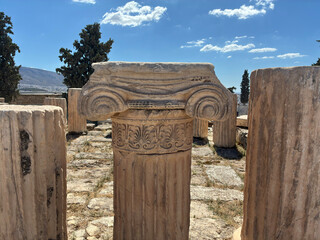 Detailed close up of Parthenon column capital with scroll carvings in Athens, ancient marble architecture under clear blue sky and sunlight.