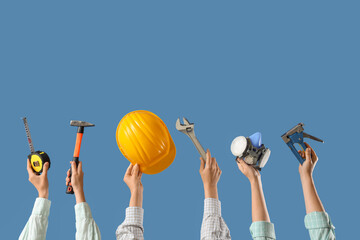 Hands with hardhat and construction tools on blue background