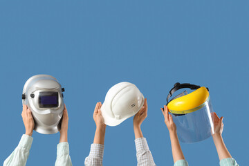 Hands with hardhat, face shield and welding mask on blue background