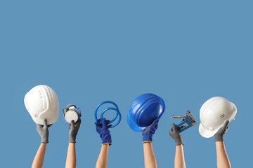 Hands with hardhat and construction tools on blue background
