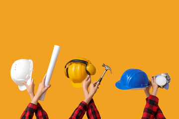 Hands with hardhats and construction tools on yellow background