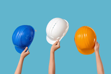 Hands with hardhats on blue background