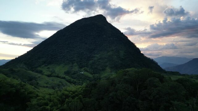 Aerial footage of Cerro Tusa, the pyramid-shaped mountain near Venecia in the Antioquia region of Colombia, rising from the surrounding highlands of the Western Andes during a picturesque sunset