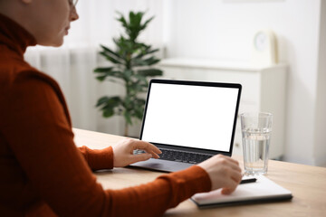 Fototapeta premium Woman working with laptop at wooden table indoors, closeup. Mockup for design