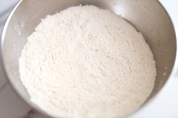 Stainless steel bowl of flour on marble countertop for baking and cooking