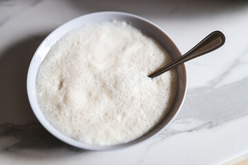 Frothy creamy dessert in white bowl on marble surface