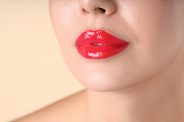 Naklejka premium Woman with beautiful red lipstick on her lips against beige background, macro view