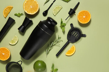 Modern bartender kit and cocktail ingredients on green background