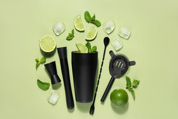 Modern bartender kit and cocktail ingredients on green background
