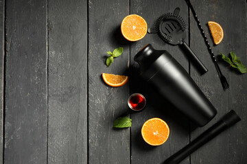 Modern bartender tools and cocktail ingredients on black wooden background