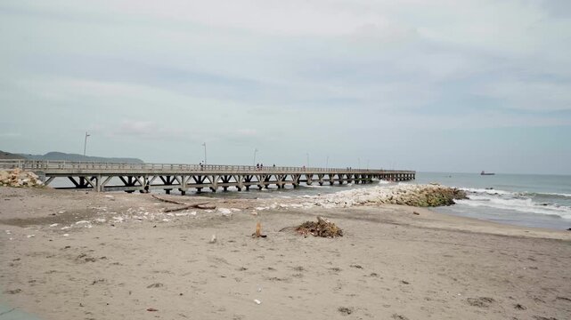 Long pier on a sandy beach extending into the ocean in puerto colombia on a cloudy day