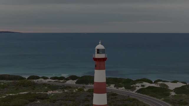 Aerial circling shot of a lighthouse, closer to subject and slower moving. Soft light from susnrise.