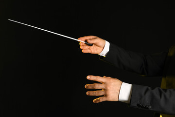 Hands of male conductor with baton on black background