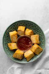 Overhead view of fried tofu with pepper sauce, top view of pan fried soya bean tofu and sauce in a plate