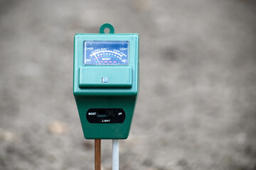 A close-up of a soil meter measuring moisture and light levels in the garden.