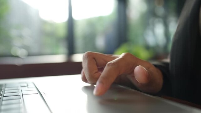 Close up of woman s finger using laptop trackpad in soft daylight. Technology, UX interaction, and digital control concept.