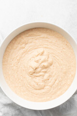 Overhead of moi moi mixture in a white ceramic bowl, top view of nigerian bean pudding being mixed, process of making nigerian moi moi
